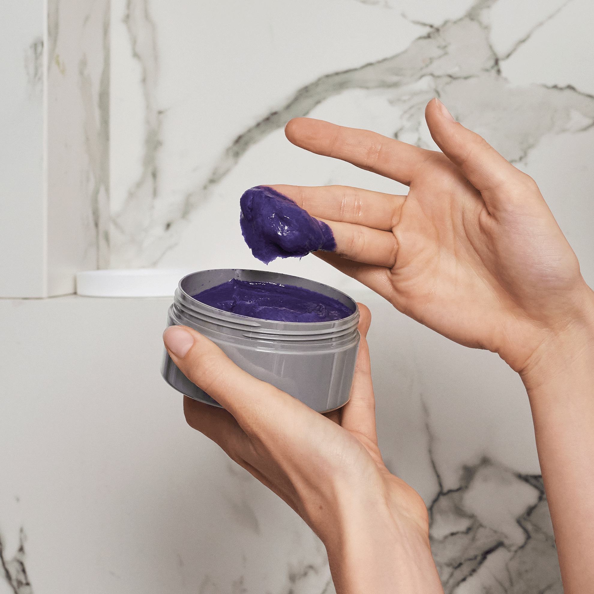 Một người đang cầm lọ kem màu tím