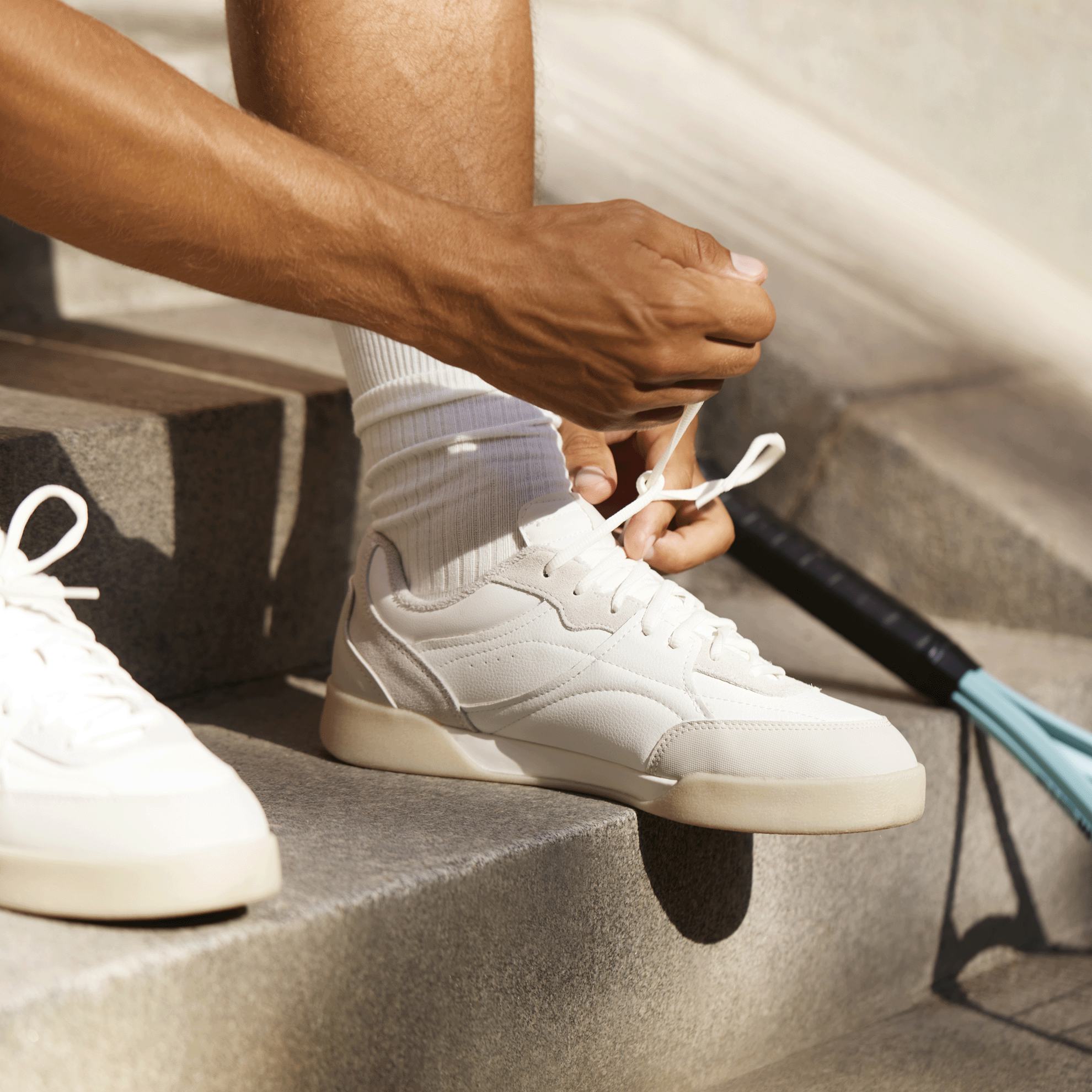 Một người đang thắt dây giày tennis.