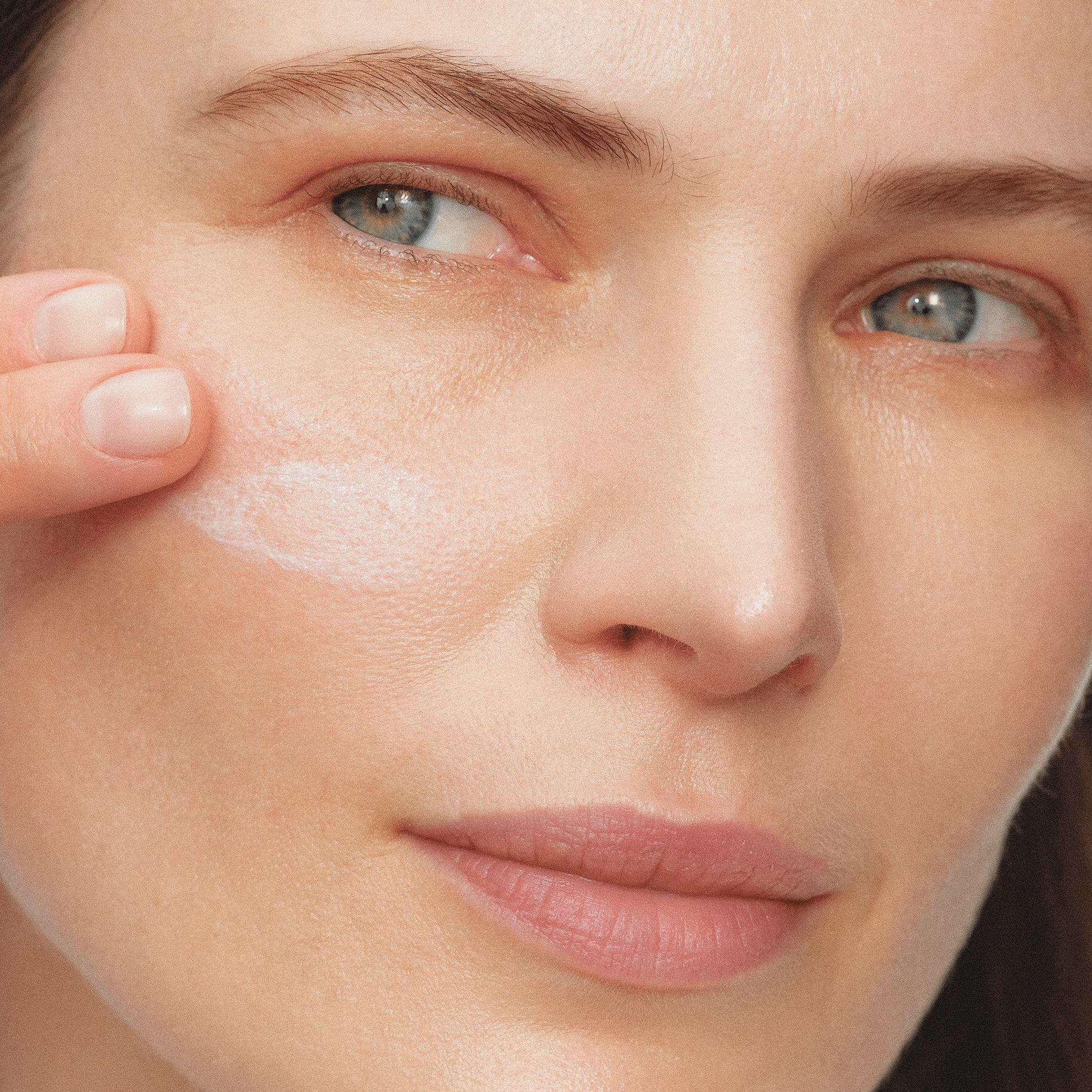 Một phụ nữ đang thoa kem lên mặt.