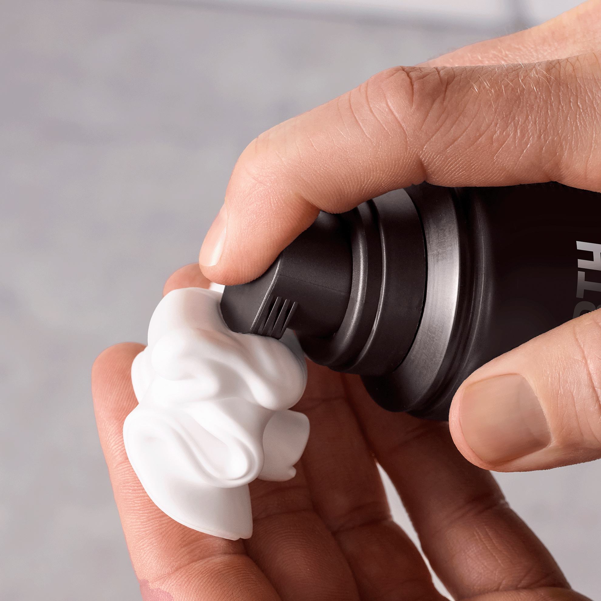 một người đang dùng chai màu đen để bôi bọt lên một vật thể màu trắng