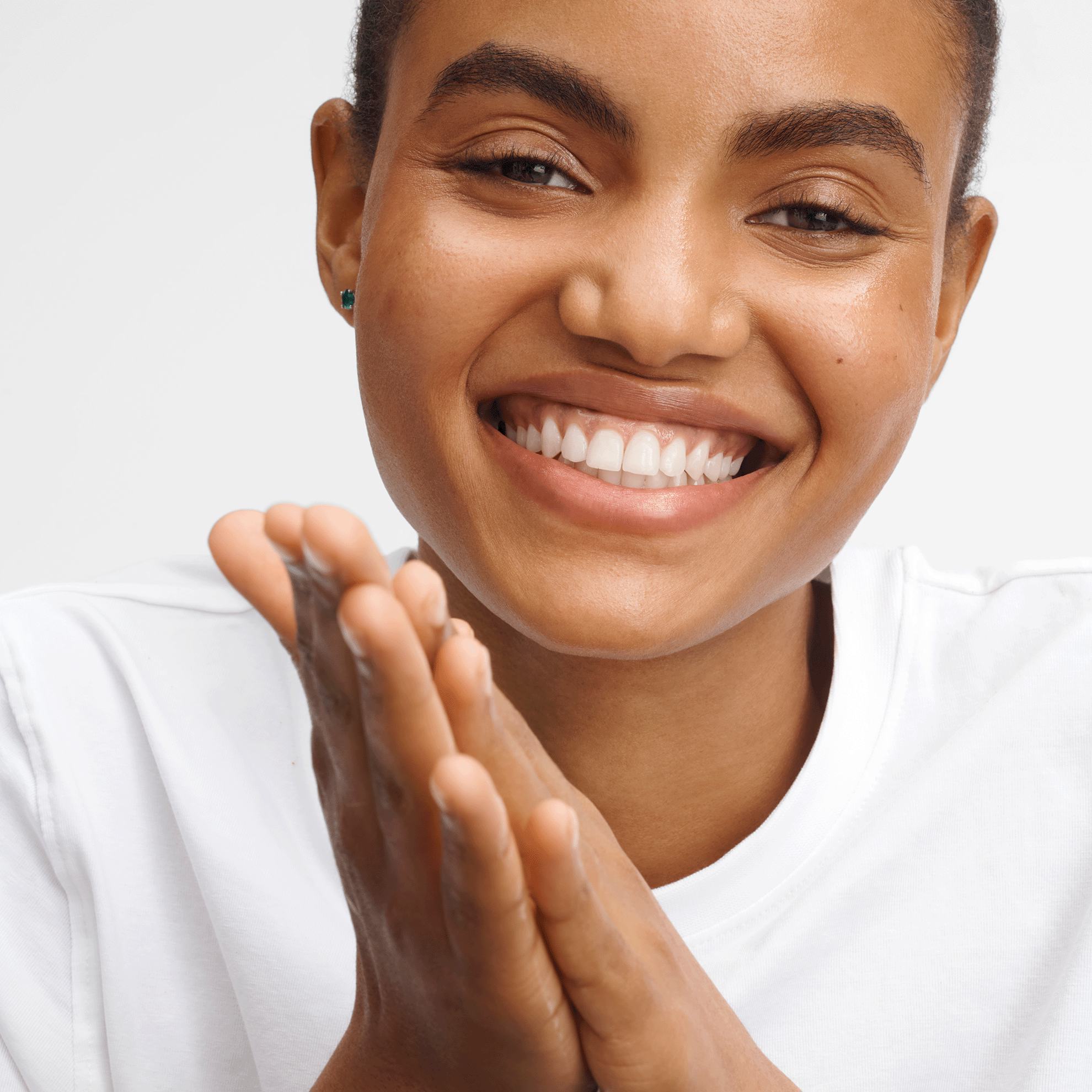 một người phụ nữ mỉm cười với hai tay chắp lại