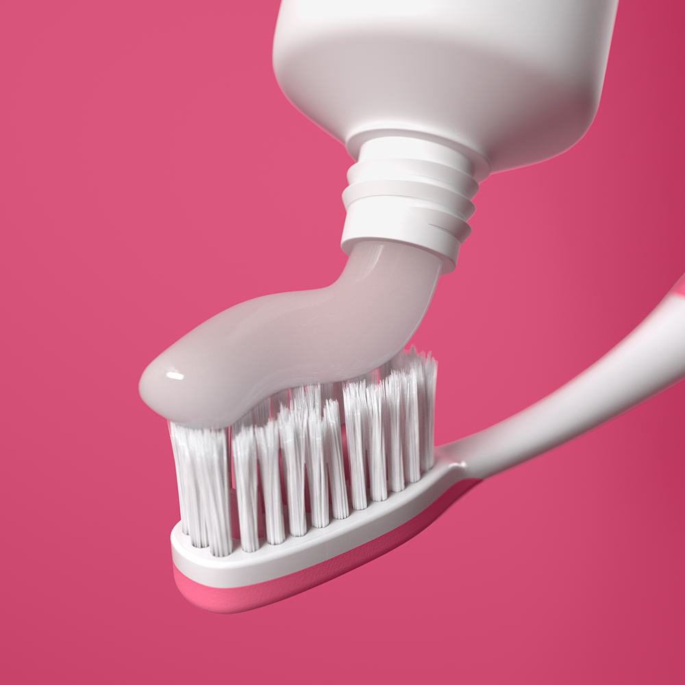 một tuýp kem đánh răng đang được bôi lên bàn chải đánh răng