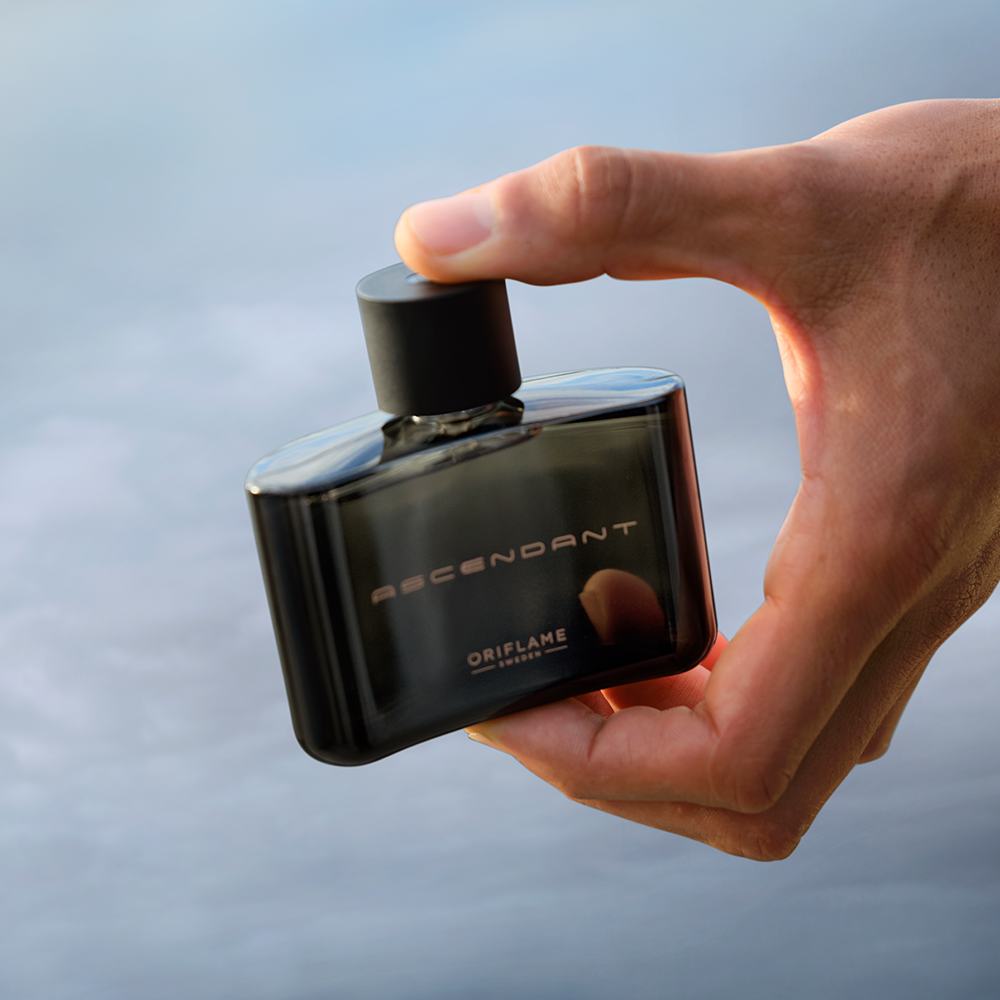 một bàn tay cầm một chai nước hoa nhỏ