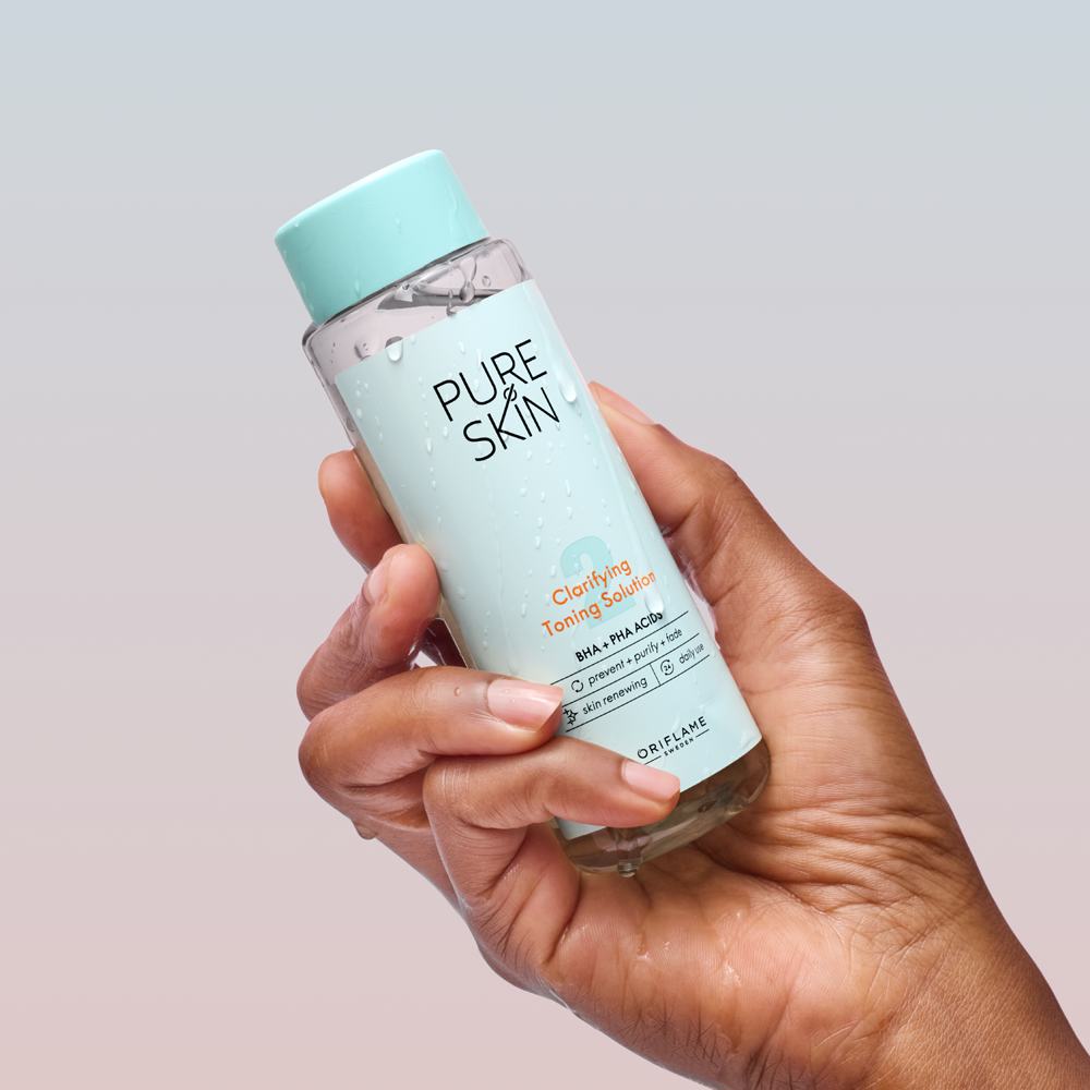 Một bàn tay cầm chai sản phẩm chăm sóc da