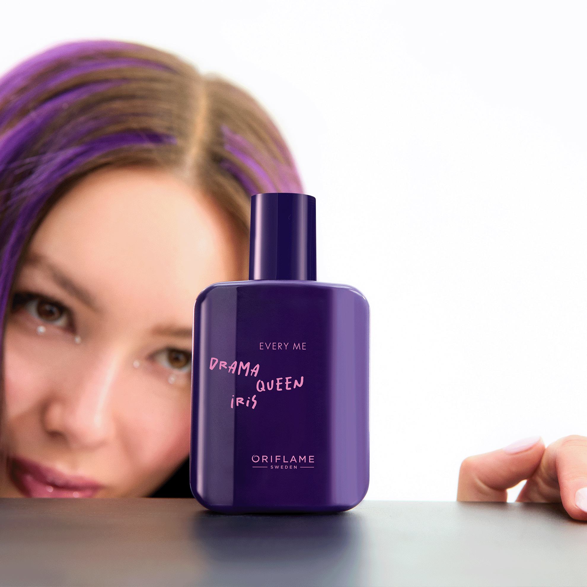 Một phụ nữ có mái tóc tím và chai nước hoa màu tím.