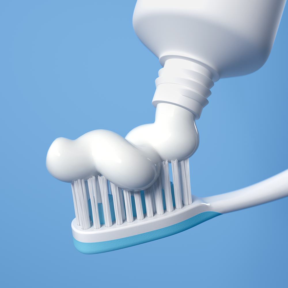 một tuýp kem đánh răng đang được bôi lên bàn chải đánh răng